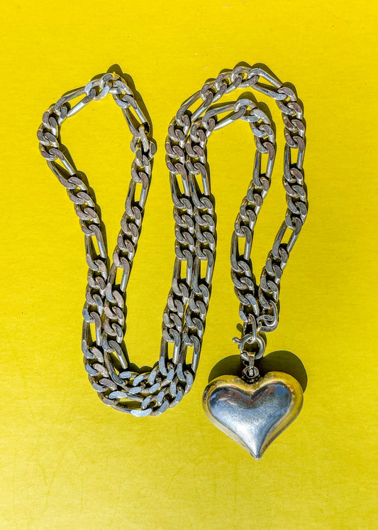 Silver chain with heart pendant  on a yellow background