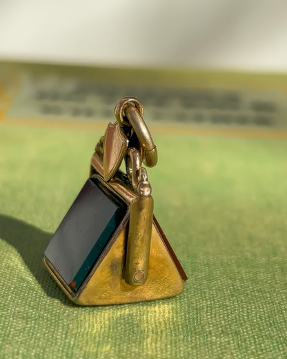 Gold fob pendant with bloodstone on a green fabric background