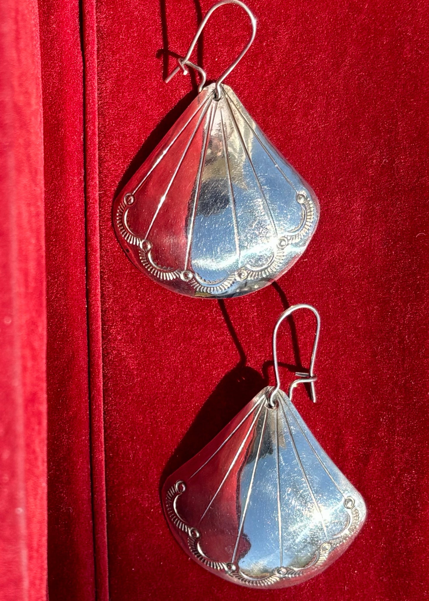 Hand tooled vintage silver earrings on a red background
