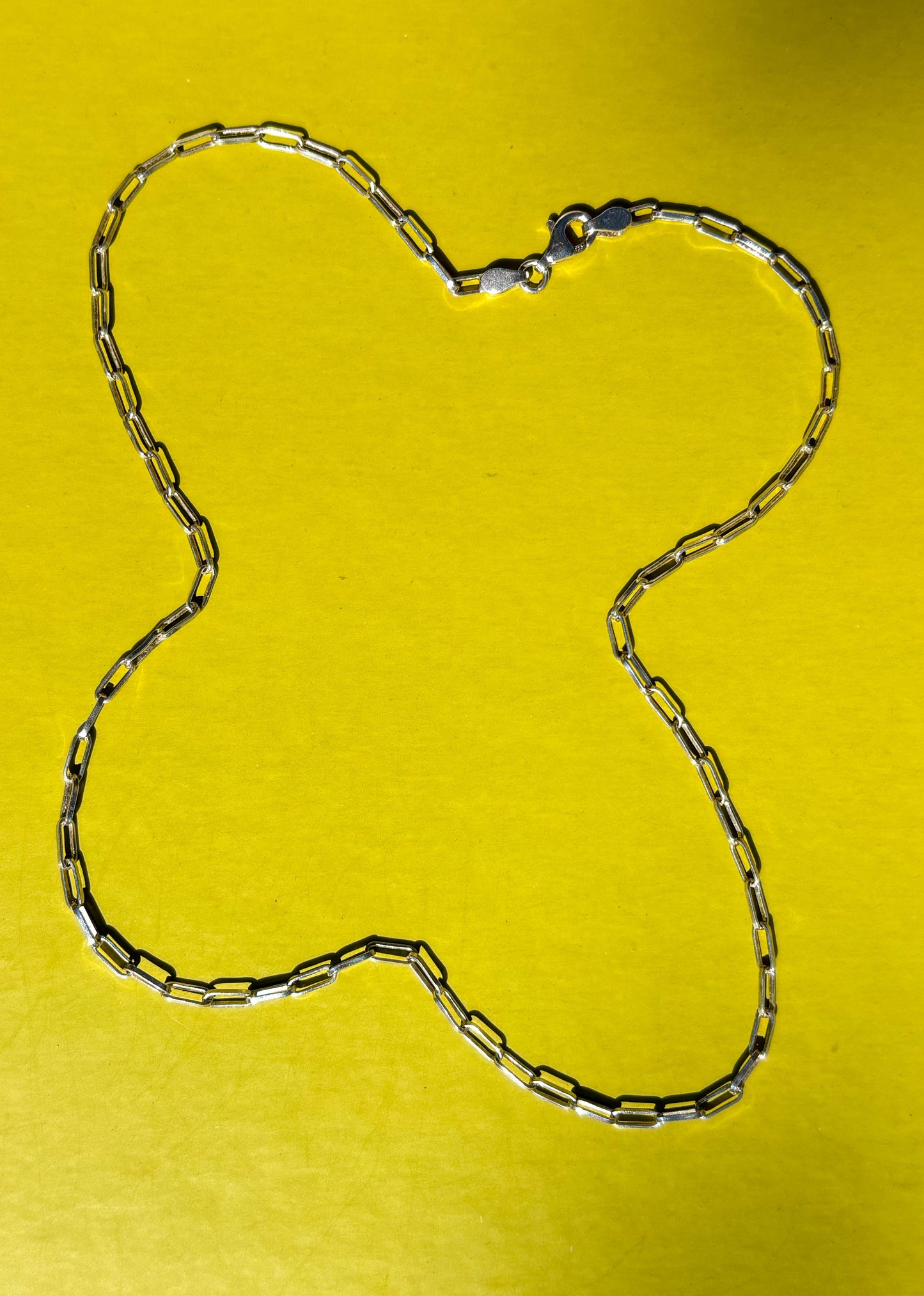 Sterling silver chain necklace on a yellow background