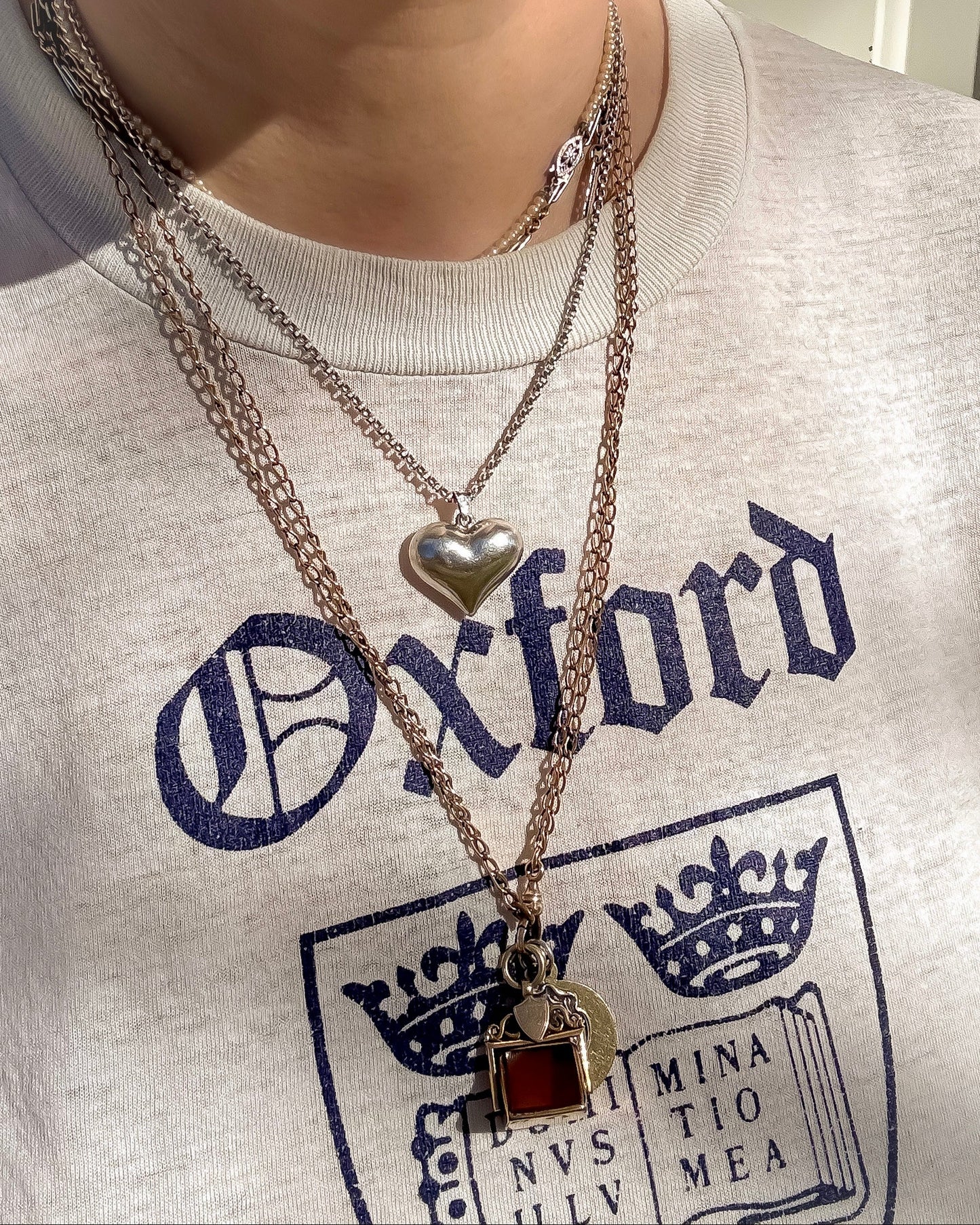 Vintage mixed length silver and gold necklaces styled in a casual way with a T shirt.