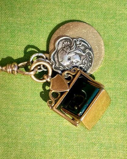 Vintage charm necklace with gold and silver pendants on a green background