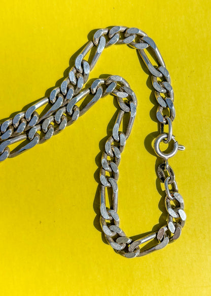 Vintage silver chain necklace on a yellow background