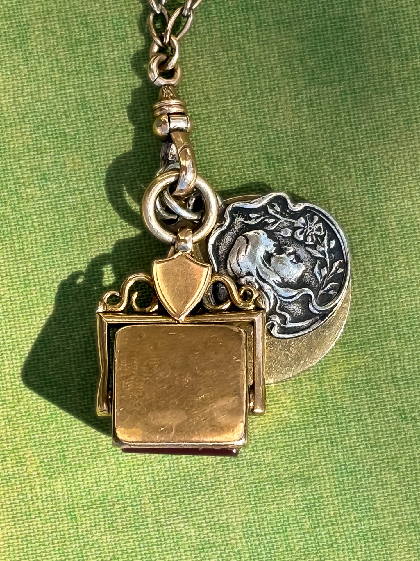 Antique yellow gold and silver pendant necklace on a green background