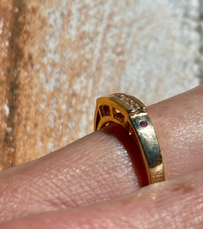 Yellow gold ring with diamonds on a finger against a textured background